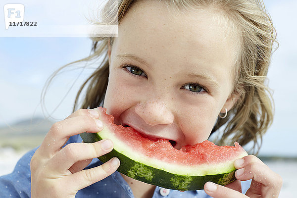Kleines Mädchen isst Wassermelone am Strand