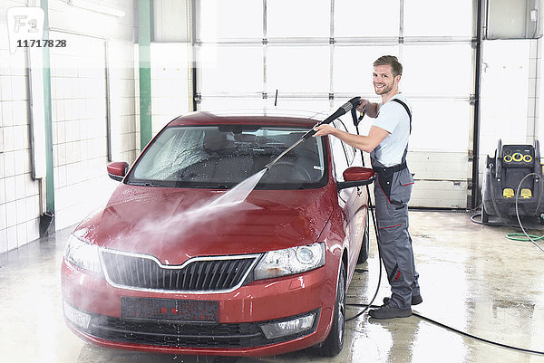 Mann reinigt Auto bei der Autowäsche