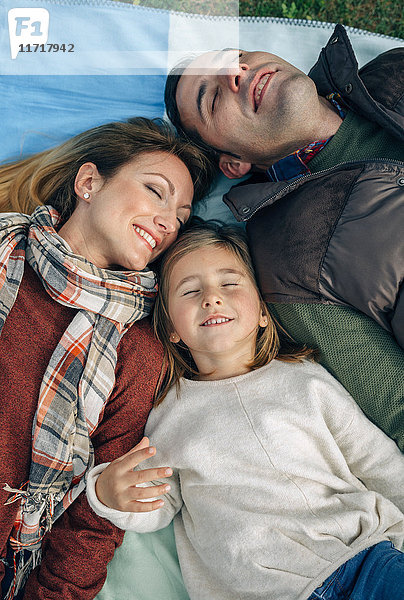 Glückliche Familie auf Decke liegend mit geschlossenen Augen