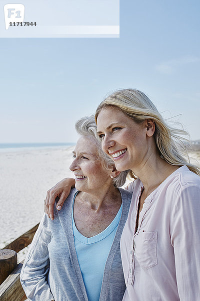 Lächelnde Seniorin mit erwachsener Tochter am Strand