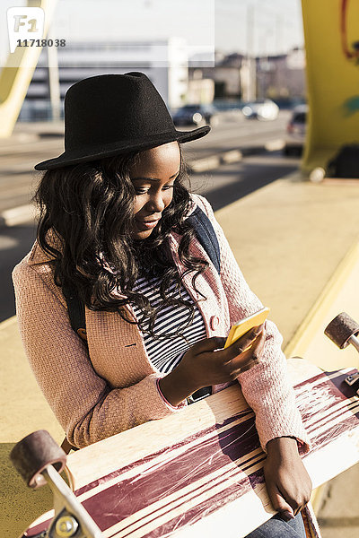 Junge Frau auf der Brücke sitzend mit dem Smartphone
