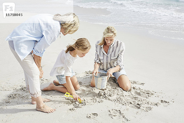 Familie spielt mit Sand am Strand
