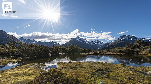 Sonne auf kleinem Bergsee mit Spiegelung einer Bergkette  Key Summit Track  Fiordland National Park  Southland Region  Neuseeland  Ozeanien