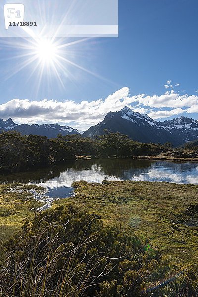 Sonne auf kleinem Bergsee mit Spiegelung einer Bergkette  Key Summit Track  Fiordland National Park  Southland Region  Neuseeland  Ozeanien