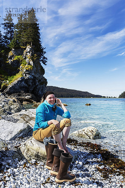 Frau sitzt auf Felsen am Ufer in der Nähe von Seldovia  Süd-Zentral-Alaska  USA