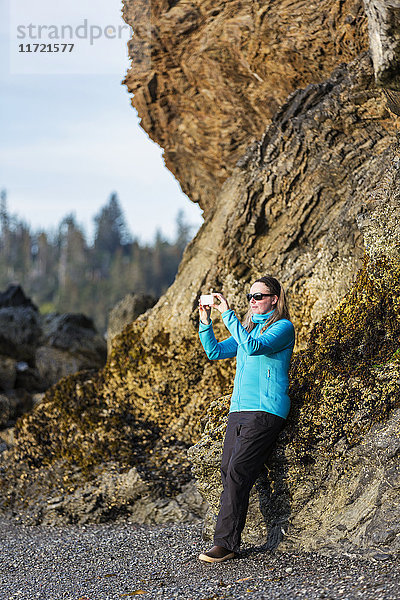 Frau fotografiert die Landschaft mit ihrem Smartphone am Strand von Homer  Süd-Zentral-Alaska  USA