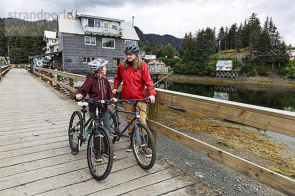 Mutter und Tochter mit Fahrrädern auf der historischen Uferpromenade von Seldovia  Süd-Zentral-Alaska  USA