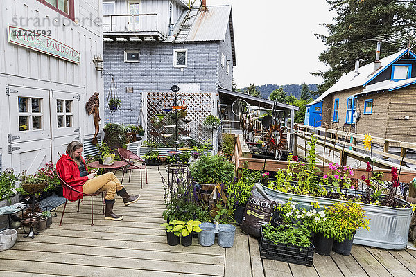 Frau sitzt auf einem Stuhl an der historischen Uferpromenade von Seldovia  Süd-Zentral-Alaska  USA