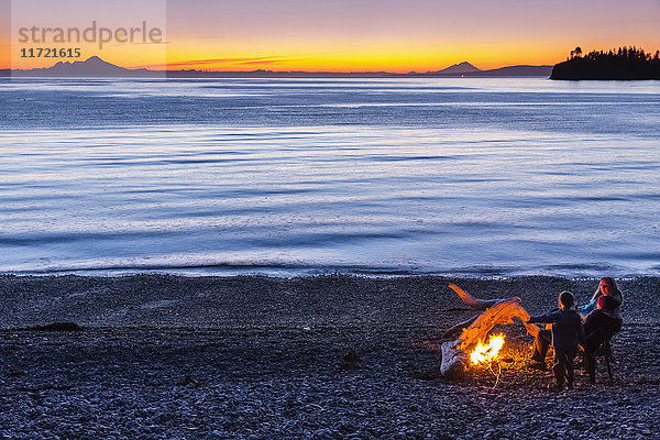 Menschen genießen ein Lagerfeuer am Strand bei Sonnenuntergang  Hesketh Island  Southcentral Alaska  USA