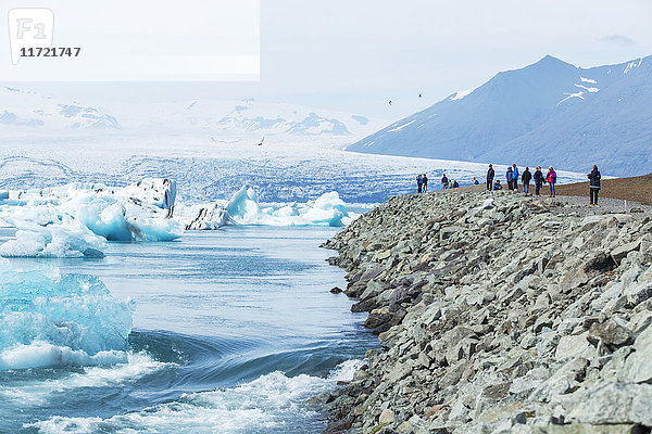 Eine Gruppe von Touristen steht am Rande eines Aussichtspunktes an der Gletscherlagune Jokulsarlon im Süden Islands  einem der beliebtesten Tour-Highlights in Island; Jokulsarlon  Island'