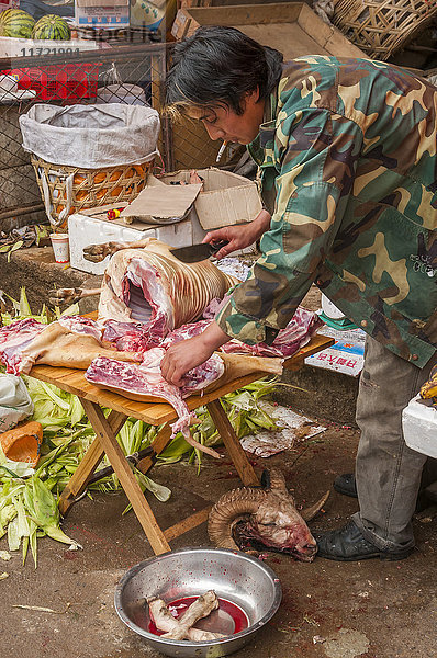 Ein Verkäufer bereitet Fleisch für den Verkauf auf diesem Markt vor  auf dem wir Angehörige verschiedener Minderheitengruppen und das tägliche Leben des berühmten Dorfes Shangrila sehen können; Shangrila  Provinz Yunnan  China .