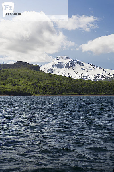 Grüne Ufer und schneebedeckte Bergkuppen auf der Unimak-Insel  der östlichsten Insel der Aleuten-Kette  von der Ikatan-Bucht aus; Südwest-Alaska  Vereinigte Staaten von Amerika'.