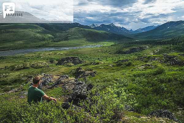 Mann sitzend mit Blick auf das Klondike-Tal entlang des Dempster Highway; Yukon  Kanada'.