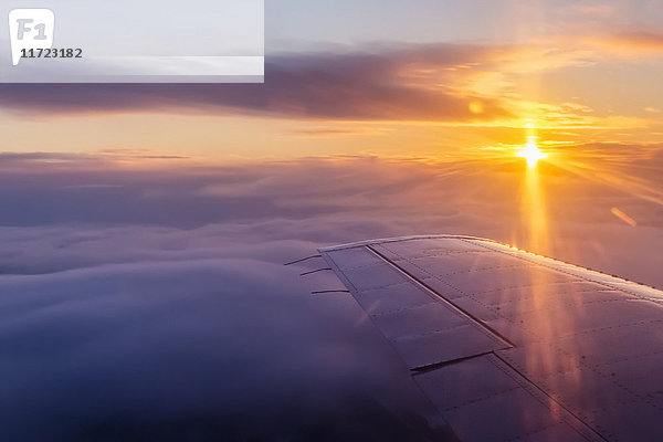 Luftaufnahme eines bewölkten Sonnenaufgangs im Winter aus dem Passagiersitz eines Verkehrsflugzeugs  Interior Alaska; Fairbanks  Alaska  Vereinigte Staaten von Amerika'.