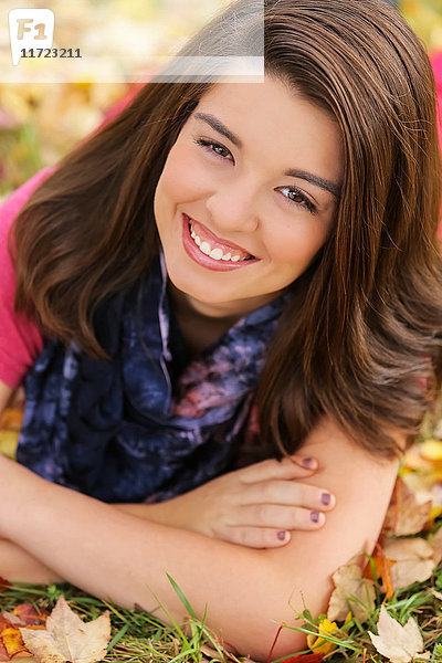 Porträt einer jungen Frau  die im Herbst im blattbedeckten Gras liegt; Oregon  Vereinigte Staaten von Amerika'.