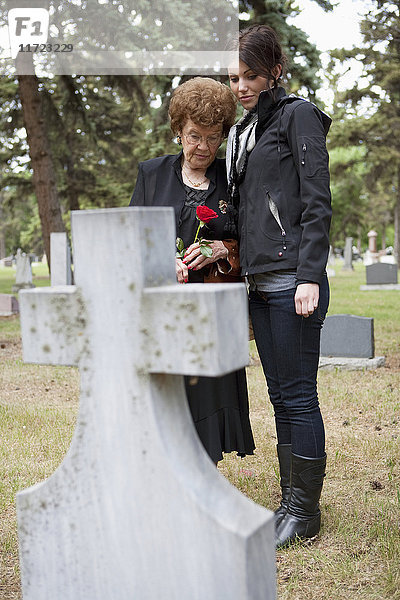 Eine Großmutter und ihre Enkelin besuchen ein Grab auf einem Friedhof in Edmonton  Alberta  Kanada.