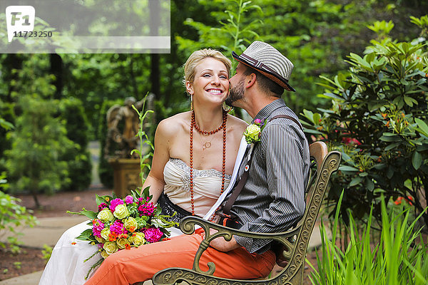 Braut und Bräutigam sitzen auf einer Bank in einem Garten; Oregon  Vereinigte Staaten von Amerika'.