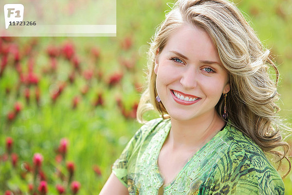 Porträt einer jungen Frau mit blondem lockigem Haar in einem Blumenfeld; Oregon  Vereinigte Staaten von Amerika'.