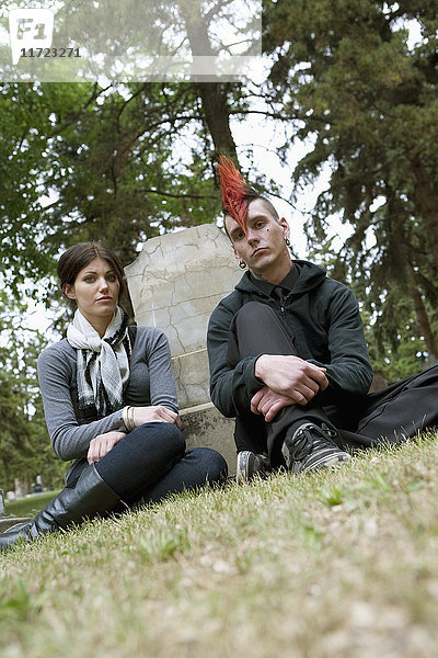 Ein junger Mann und eine junge Frau sitzen an einem Grabstein auf einem Friedhof; Edmonton  Alberta  Kanada .