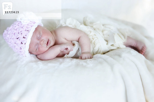 Ein neugeborenes Baby liegt schlafend auf einer weißen Decke und trägt eine rosa Strickmütze; Washington  Vereinigte Staaten von Amerika'.