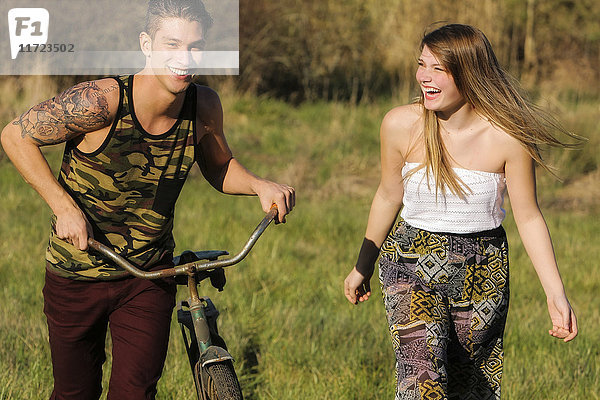 Ein junger Mann und eine junge Frau gehen zusammen  während der junge Mann ein Fahrrad schiebt; Oregon  Vereinigte Staaten von Amerika'.