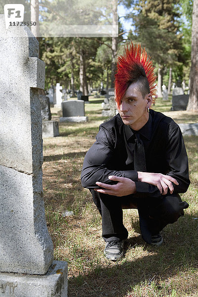 Ein junger Mann trauert an einem Grabstein auf einem Friedhof; Edmonton  Alberta  Kanada