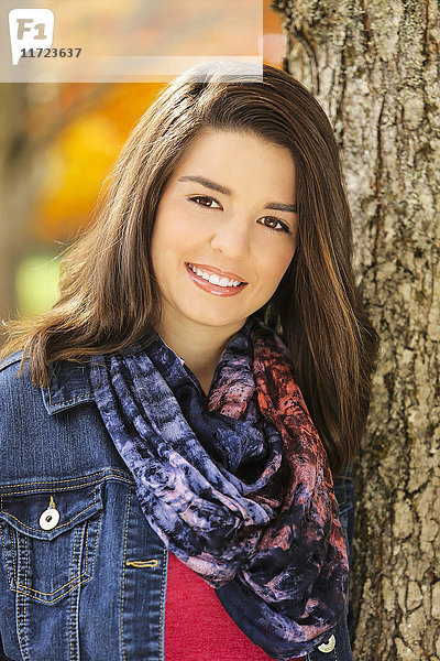 Porträt einer jungen Frau  die vor einem Baumstamm steht  mit Herbstfarben im Hintergrund; Oregon  Vereinigte Staaten von Amerika'.