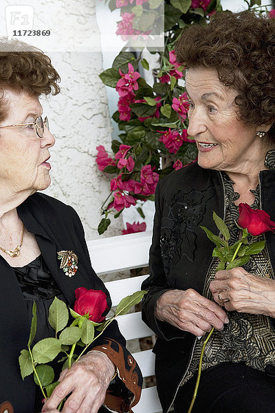 Zwei Frauen  die sich unterhalten und einzelne rote Rosen halten; Edmonton  Alberta  Kanada'.