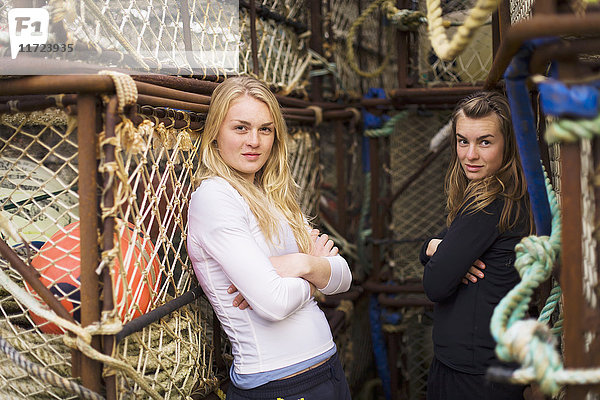 Porträt von zwei jungen Frauen vor kommerziellen Krabbenfischtöpfen im Hafen von King Cove  Alaska-Halbinsel; Südwest-Alaska  Vereinigte Staaten von Amerika'.