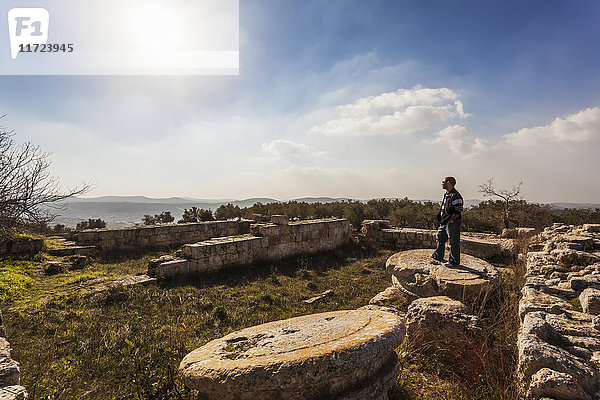 Ein junger Mann steht auf dem Sockel einer Säule in einer Ruinenstätte; Sabasita  Samaria  Israel'.