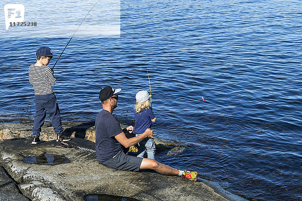 Vater mit Söhnen beim Fischen auf See