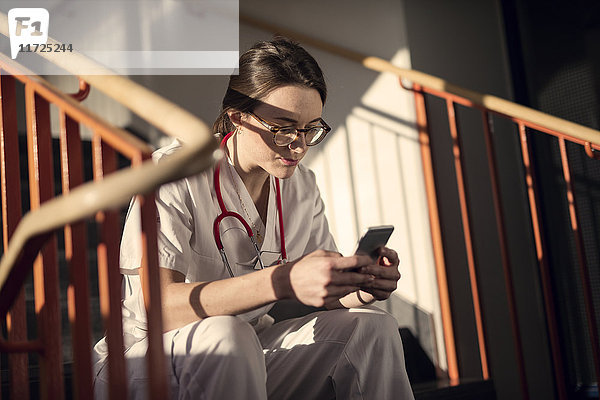 Ärztin auf der Treppe sitzend mit Smartphone