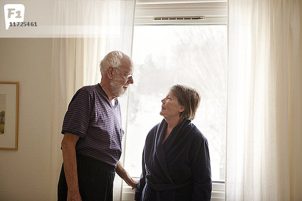 Älteres Paar steht neben dem Fenster