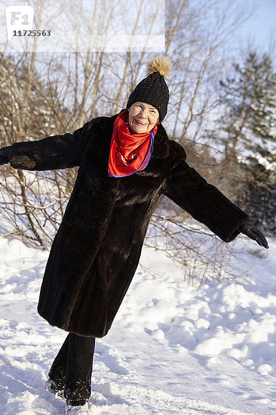 Ältere Frau beim Spaziergang im Wald im Winter