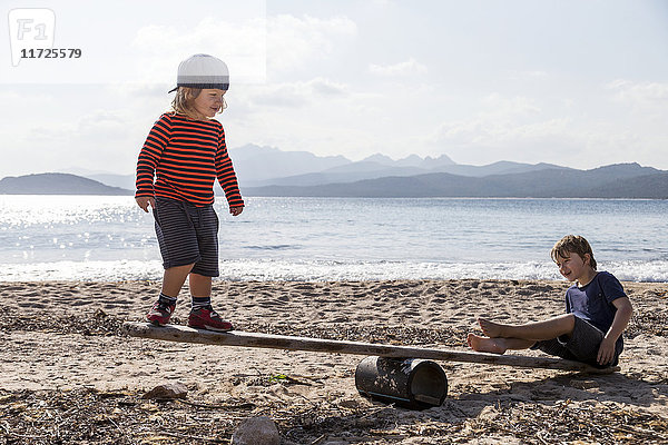 Jungen spielen Wippe am Strand