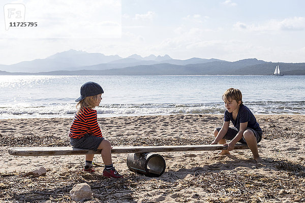 Jungen spielen Wippe am Strand