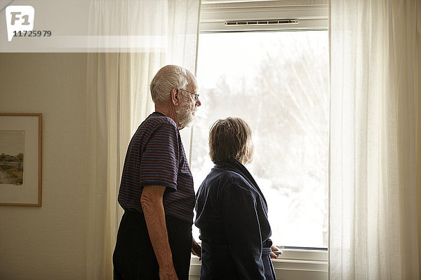 Älteres Paar schaut durch ein Fenster