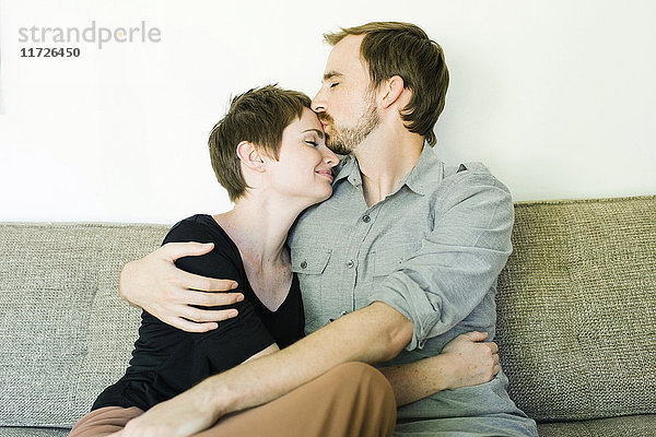 Paar umarmt und küsst sich auf dem Sofa