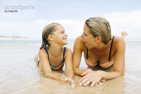 Mutter mit Tochter (6-7) am Strand liegend
