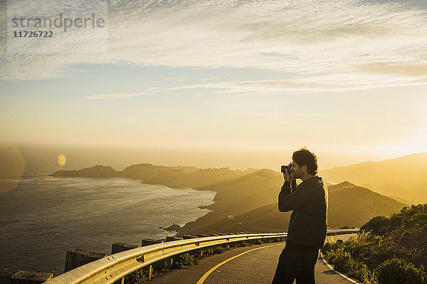 USA  Kalifornien  San Francisco  Kalifornien  Silhouette eines Mannes  der die Küstenlinie bei Sonnenuntergang fotografiert