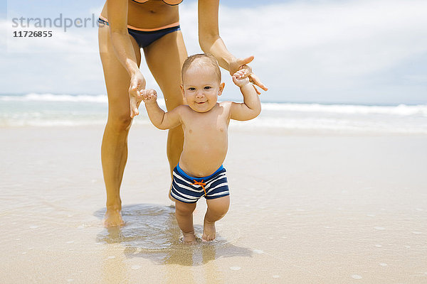 Sohn (12-17 Monate) lernt mit Mutter am Strand laufen