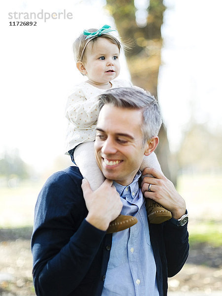 Vater trägt Tochter (12-17 Monate) auf den Schultern