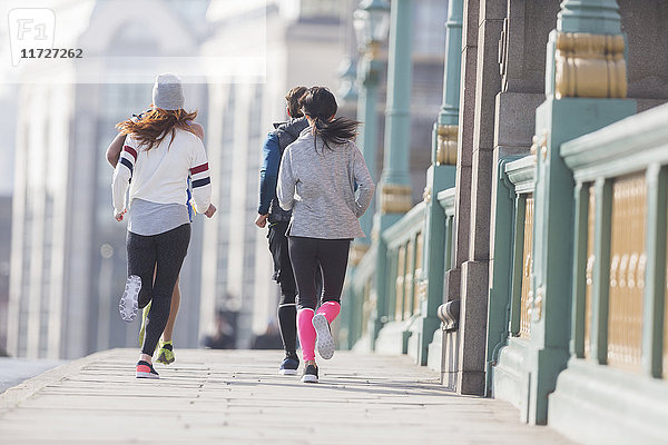 Läuferinnen und Läufer auf dem sonnigen Bürgersteig der Stadt