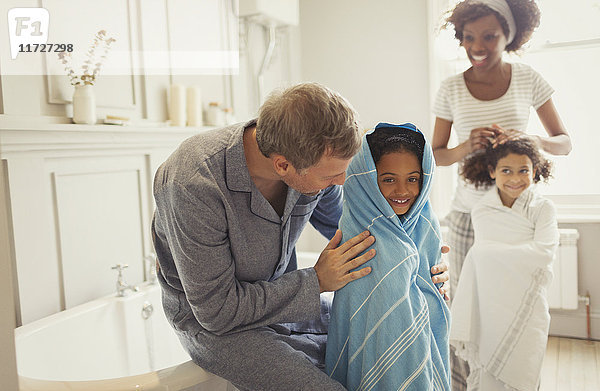 Multiethnische Eltern trocknen Töchter mit Handtüchern nach dem Baden im Bad.
