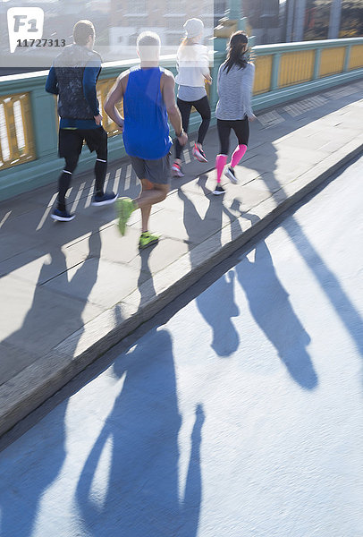 Läufer  die auf dem sonnigen Bürgersteig der Stadtbrücke laufen.