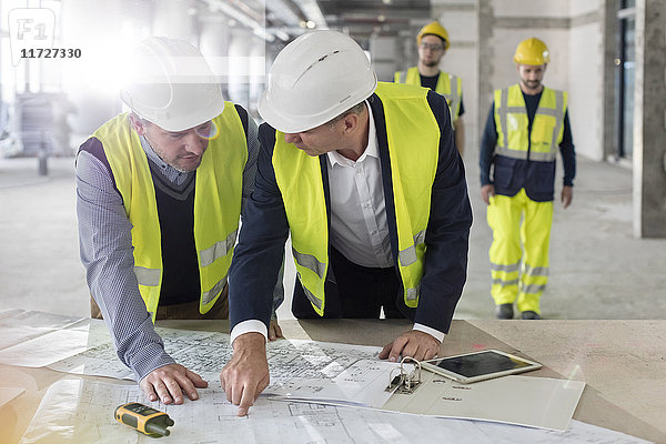 Männliche Ingenieure diskutieren Baupläne auf der Baustelle
