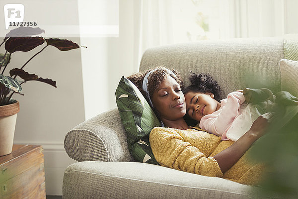 Gelassene Mutter und Tochter beim Schlafen und Kuscheln auf dem Sofa