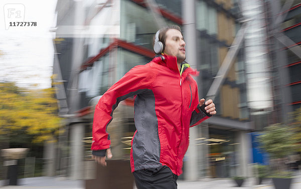Mann läuft mit Kopfhörern an einem städtischen Gebäude vorbei.