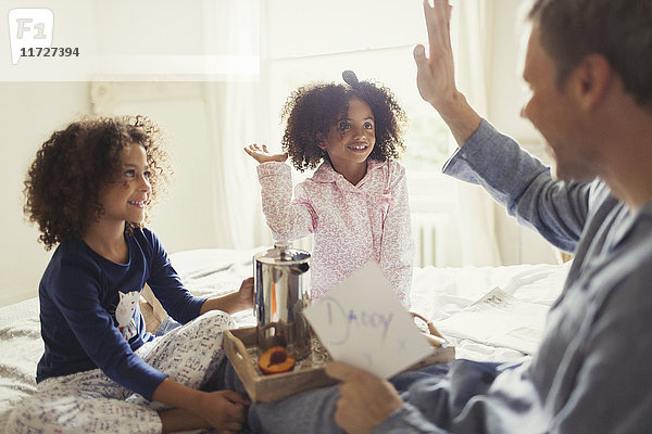 Vater erhält Vatertagskarte von Töchtern und High-Fiving im Bett