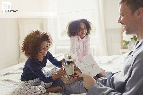 Töchter  die am Vatertag Kaffee und Karte an Vater im Bett servieren.